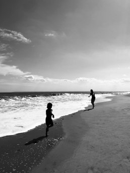 Black and white photography child running on the beach to her mum